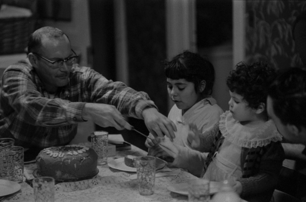 Gene sharing the cake with two of his children, 1956