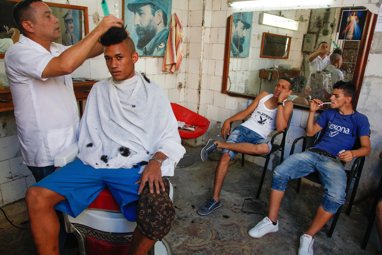 Miguel at barber shop, 2012, © Mariette Pathy Allen. A lot of the women have boyfriends who are half their age. A lot of young gay men come from outside Havana and are "kept" by trans women,  who are mostly prostitutes because of the difficulty of finding work elsewhere due to their gender identification.