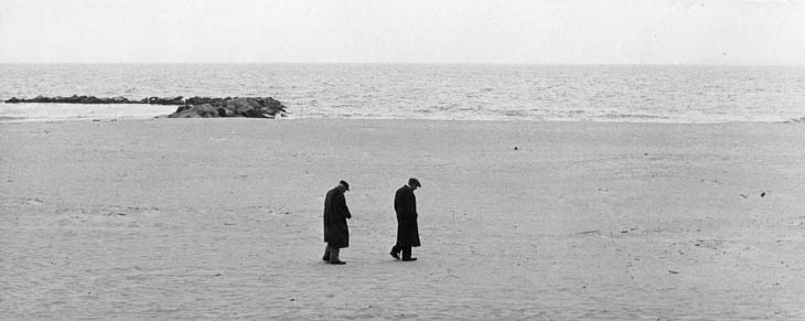 Two men walking on the beach, 1950