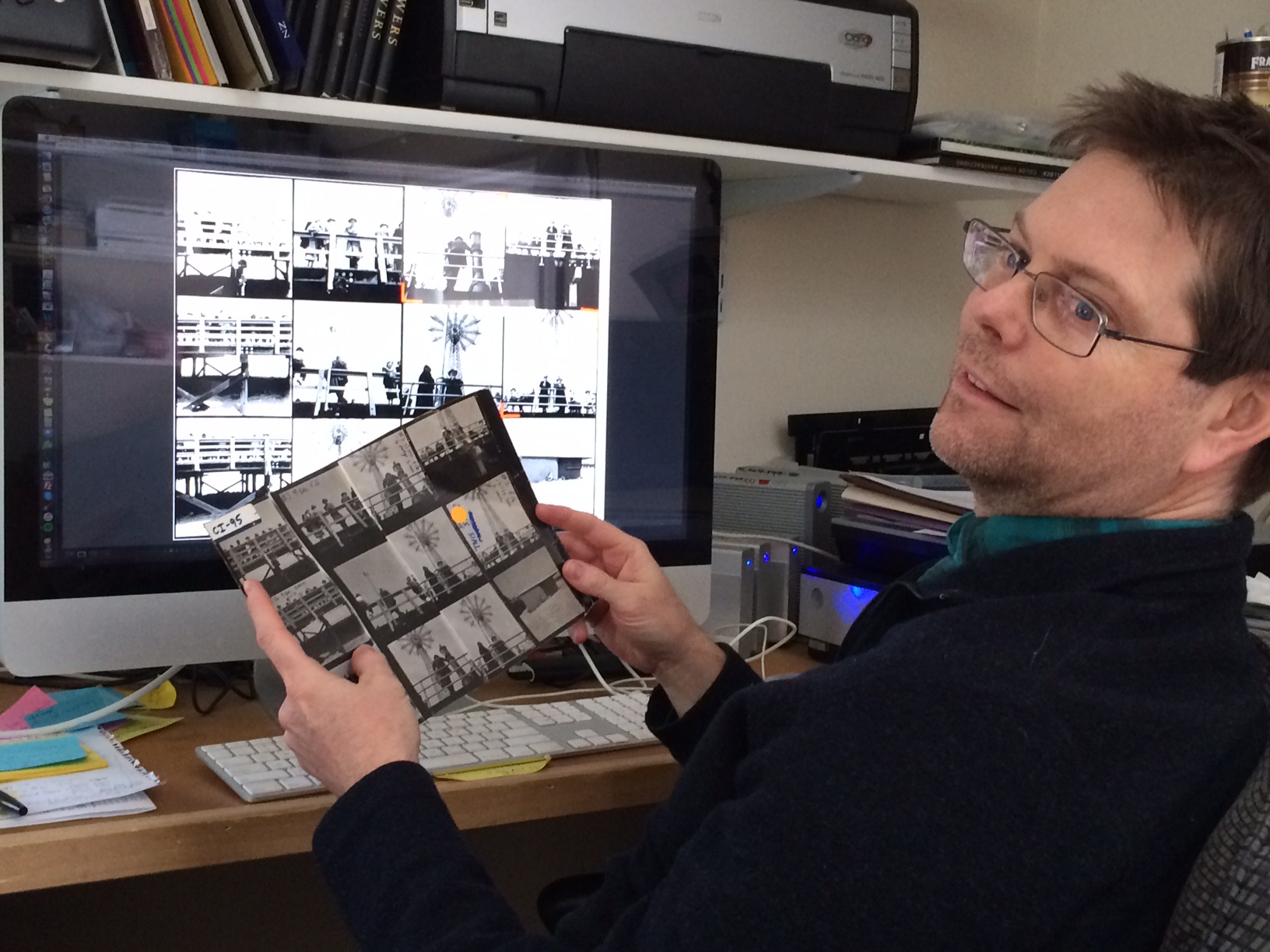 John holding up the original contact sheet ih comparison to screen view.  